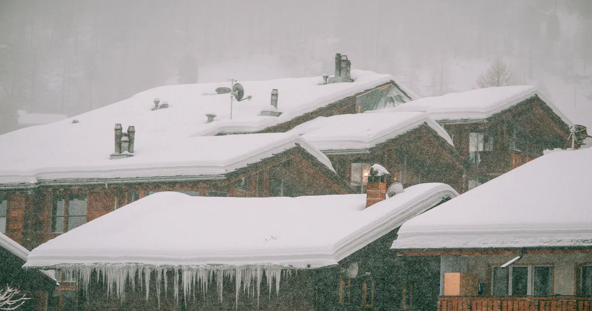 Toits chargés d'une épaisse couche de neige et de glaçons pendant une tempête
